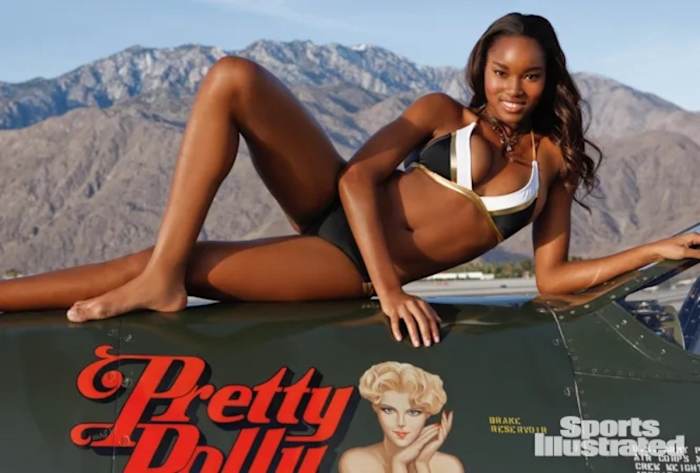 Damaris Lewis poses atop a green plane in a black, white and gold triangle bikini.